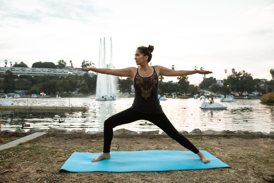 Woman practicing a yoga pose by a tranquil lake at sunset